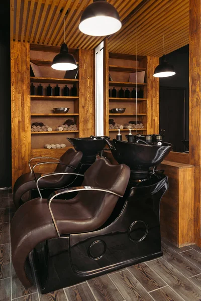 Empty leather chairs and sinks in modern hair salon — Stock Photo