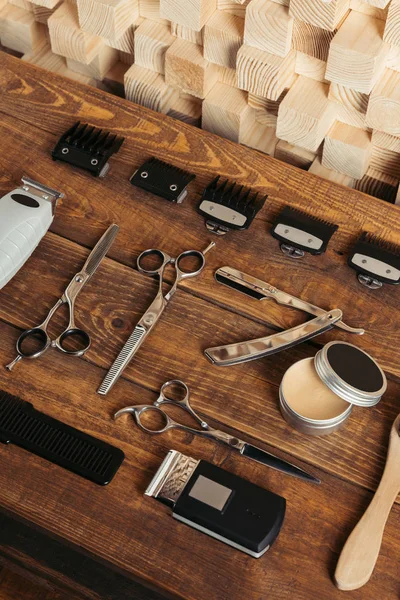 Vista de ángulo alto de varias herramientas de peluquería profesional en la superficie de madera en el salón de belleza - foto de stock