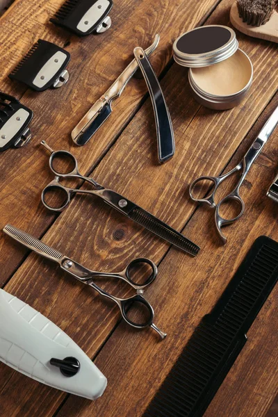 Vista ad alto angolo di vari strumenti da barbiere professionali su superficie in legno in barbiere — Foto stock