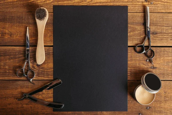 Top view of professional barber tools and blank black card on wooden table — Stock Photo