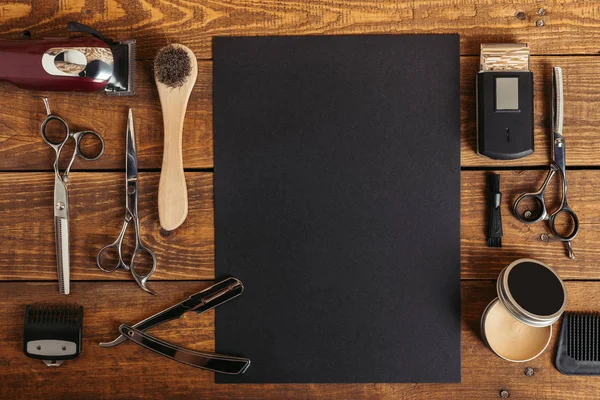 Top view of professional barber tools and blank black card on wooden table — Stock Photo