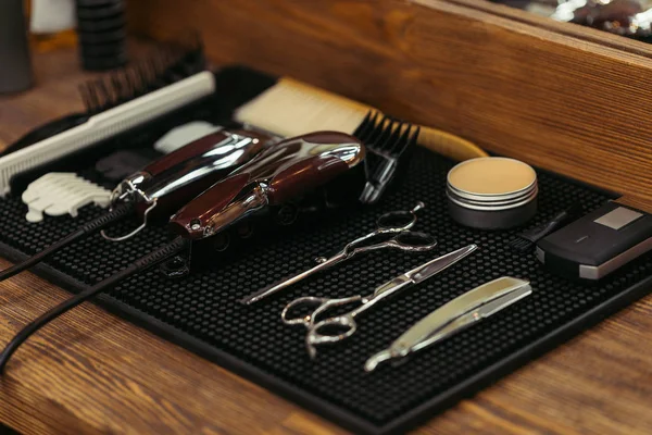 Vista de cerca del conjunto de herramientas profesionales de peluquería en el estante de madera en la barbería - foto de stock