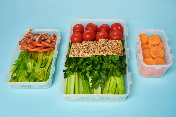 Close up view of arrangement of food containers full of healthy vegetables, meat slices and cookies on blue backdrop — Stock Photo