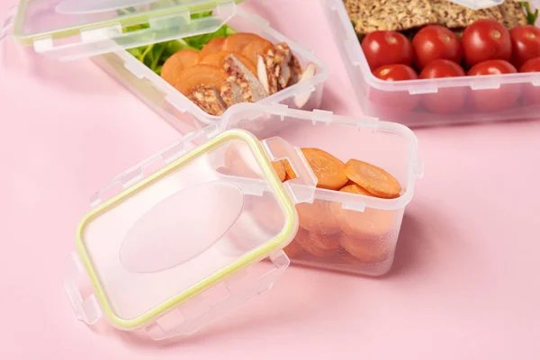 Close up view of healthy food arranged in food containers on pink backdrop — Stock Photo