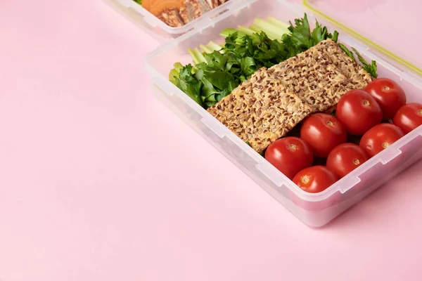 Close up view of healthy food arranged in food containers on pink backdrop — Stock Photo