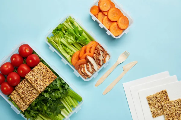 Vista dall'alto di disposizione di contenitori alimentari con alimenti freschi sani e posate isolate su blu — Foto stock