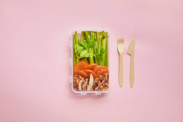 Flat lay with healthy food arranged in food container and cutlery isolated on pink — Stock Photo