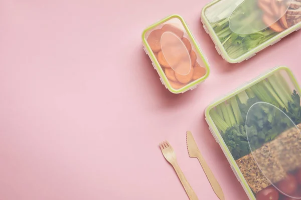 Flat lay with healthy food arranged in food containers and cutlery isolated on pink — Stock Photo