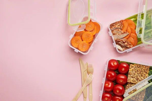 Flat lay with healthy food arranged in food containers and cutlery isolated on pink — Stock Photo