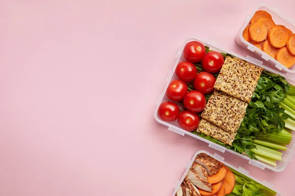 Flat lay with  fresh vegetables and cookies arranged in food containers isolated on pink — Stock Photo