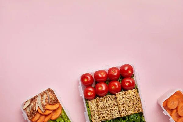 Yacía plana con alimentos saludables dispuestos en recipientes de alimentos aislados en rosa - foto de stock