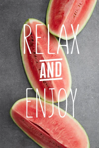 Flat lay with watermelon pieces on grey concrete tabletop, with 