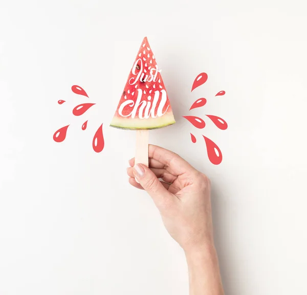 Cropped view of peron holding watermelon slices on stick, 