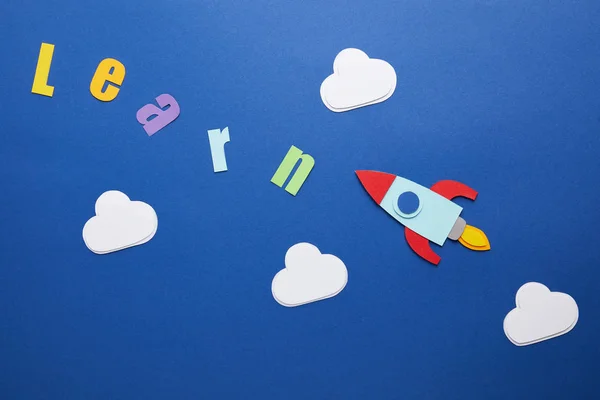 Vista superior de aprender letras com nuvens e foguete no fundo azul — Fotografia de Stock