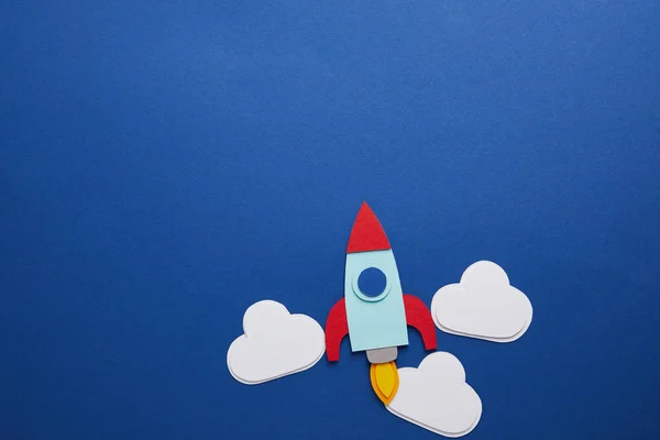 Clouds and rocket on blue background with copy space — Stock Photo