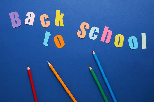 Vista dall'alto di iscrizione a scuola con matite su sfondo blu — Foto stock