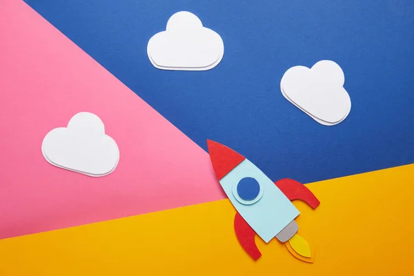 Top view of clouds and colorful rocket on creative paper background — Stock Photo