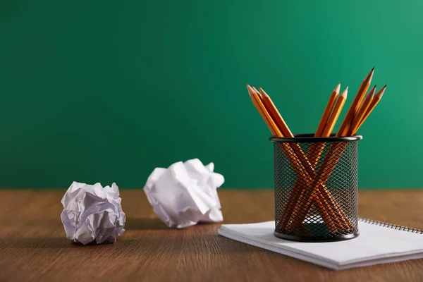 Pencils, copybook and crumpled papers with green chalkboard on background — Stock Photo