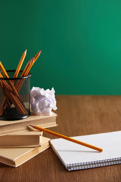 Books, copybook, crumpled paper and pencils on wooden table — Stock Photo