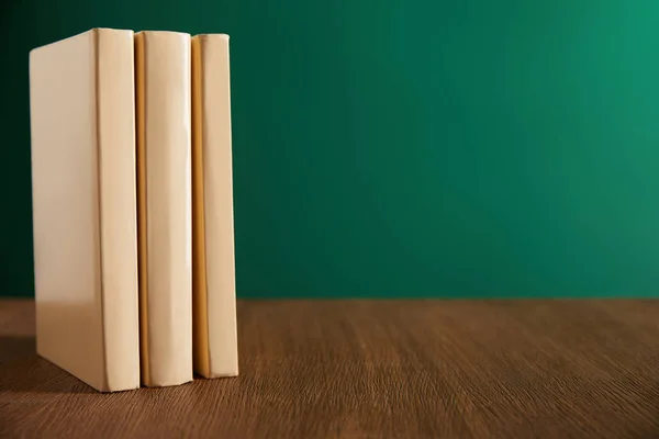 Three books on wooden table with chalkboard on background — Stock Photo