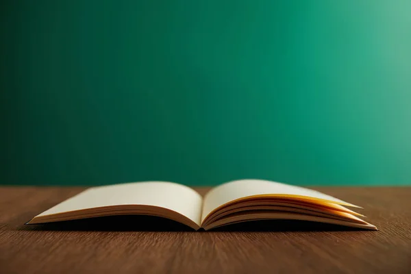 Open book on wooden table with chalkboard on background — Stock Photo