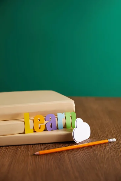 Books, pencil, cloud sign and learn lettering on wooden table — Stock Photo