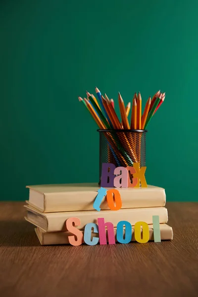 Buntstifte und Bücher auf Holztischplatte mit Schulschriftzug — Stockfoto