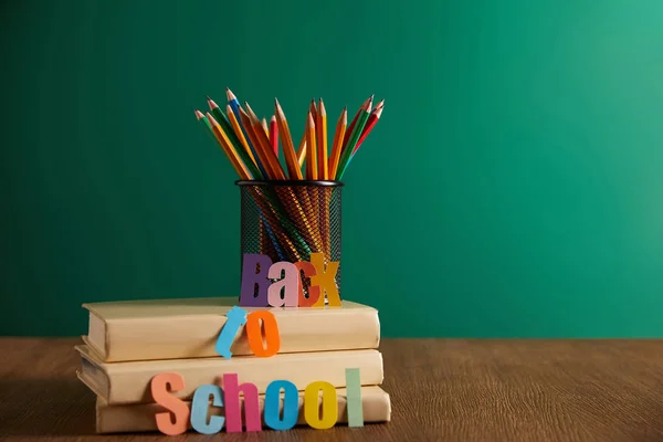 Красочные карандаши на книгах со школьной надписью, доска на заднем плане — стоковое фото