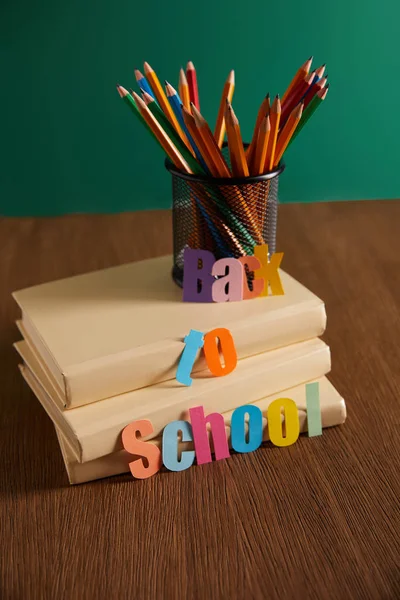 Matite e libri su tavolo in legno con lettering back to school — Foto stock