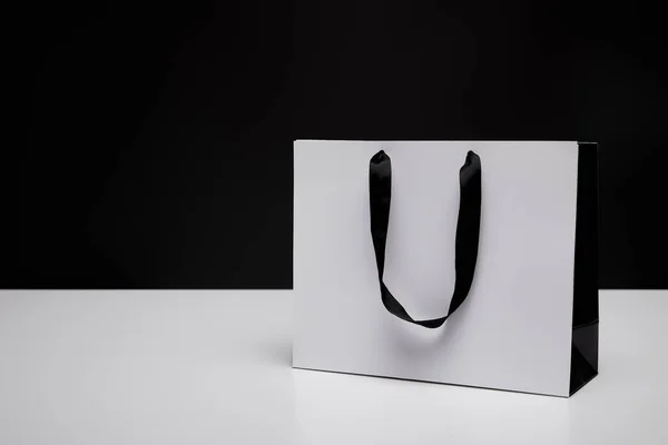 Una bolsa de compras de papel blanco sobre mesa blanca aislada sobre negro - foto de stock