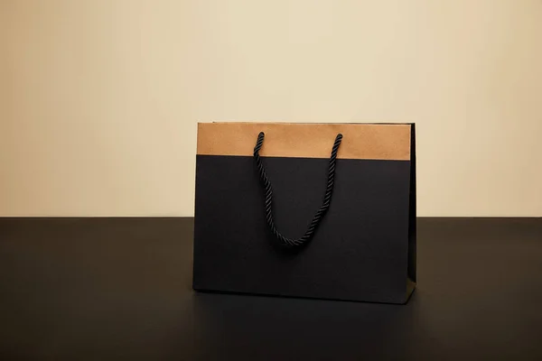 One black shopping bag on black table isolated on beige — Stock Photo