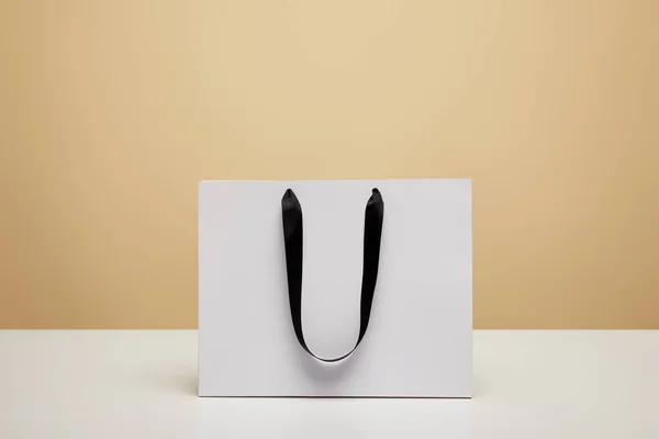 One white shopping bag on white tabletop isolated on beige — Stock Photo