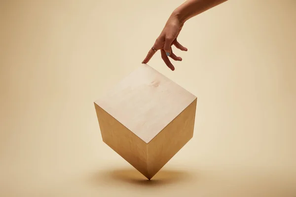 Cropped image of woman touching wooden cube on beige — Stock Photo