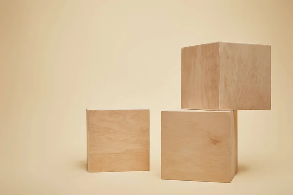 Trois cubes en bois brun isolés sur beige — Photo de stock