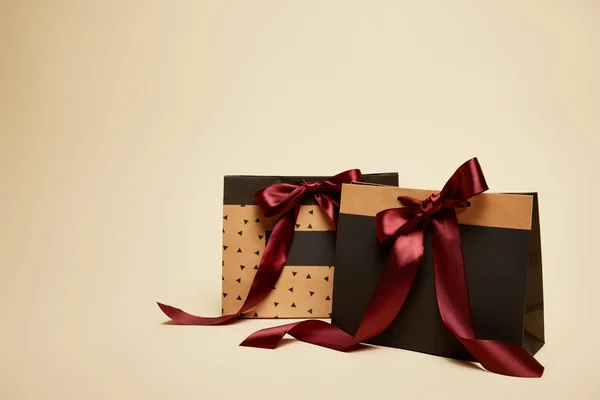 Paper brown and black shopping bags with bows isolated on beige — Stock Photo