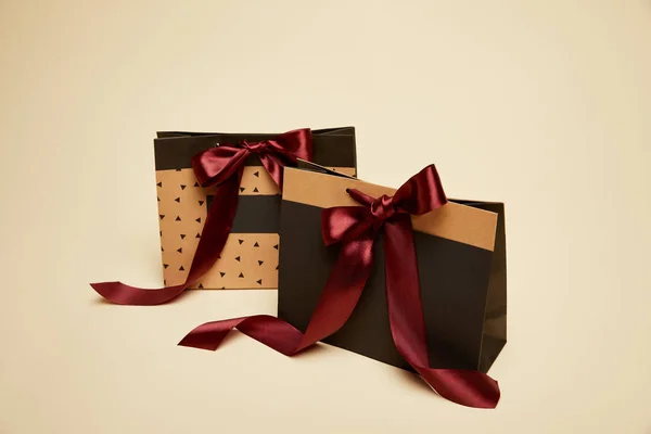 Fashionable shopping bags with burgundy bows isolated on beige — Stock Photo