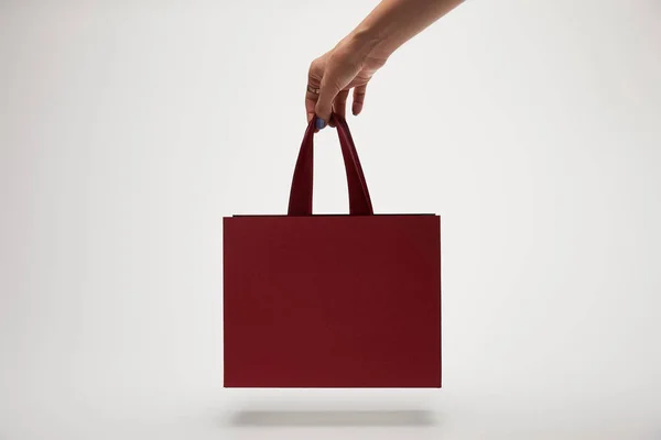 Cropped image of woman holding burgundy shopping bag in hand isolated on white — Stock Photo