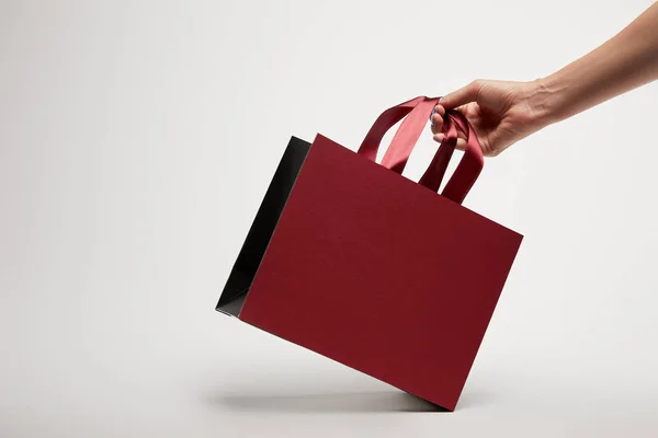 Cropped image of woman holding burgundy shopping bag on white — Stock Photo