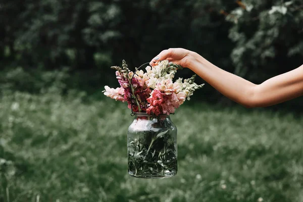 Image recadrée de la femme tenant pot en verre avec diverses fleurs colorées — Photo de stock