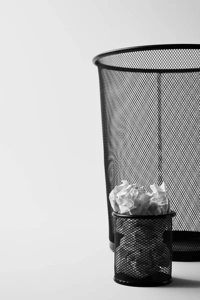 Primer plano de grandes y pequeñas papeleras de oficina con papeles arrugados en blanco - foto de stock