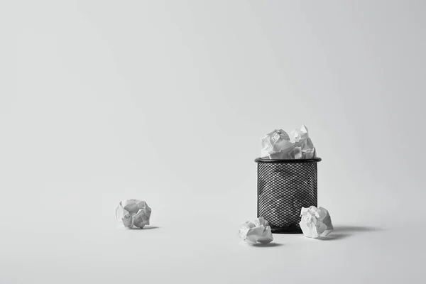 Poubelle de bureau avec des papiers froissés sur surface blanche — Photo de stock