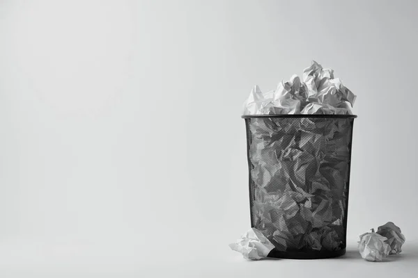 Poubelle de bureau avec papiers froissés sur surface blanche — Photo de stock