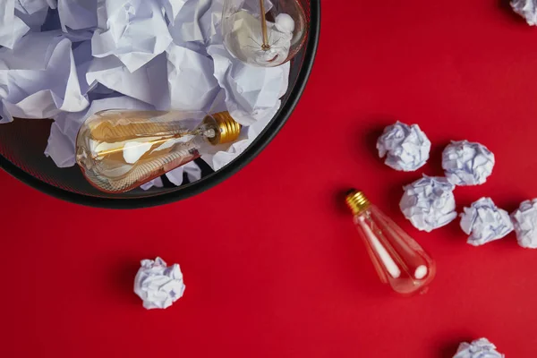 Top view of office trash can with crumpled papers and vintage incandescent lamps on red tabletop — Stock Photo