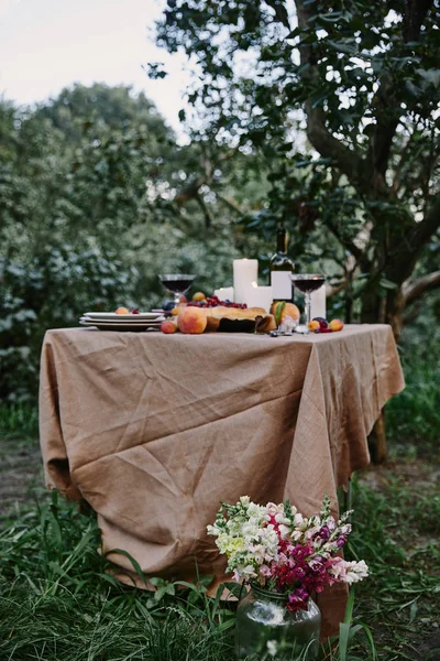 Mesa servida no jardim, buquê de flores na grama — Fotografia de Stock
