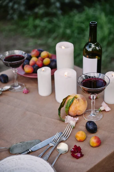 Velas e vinho tinto na mesa no jardim para o jantar romântico — Fotografia de Stock