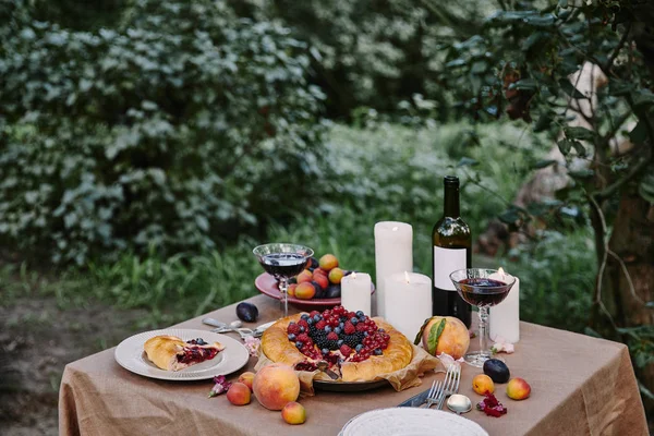 Leckere leckere Beerenkuchen und Wein auf dem Tisch im Garten — Stockfoto