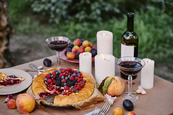 Torta di bacche appetitosa saporita e candele su tavolo in giardino — Foto stock