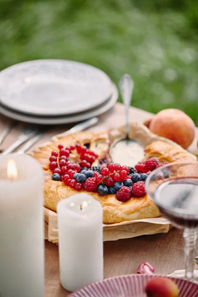 Kuchen mit Beeren, Kerzen auf dem Tisch im Garten — Stockfoto
