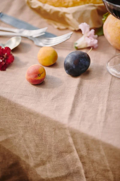 Plums and utensils on beige tablecloth in garden — Stock Photo