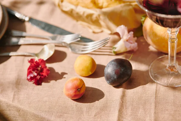 Ameixas e utensílios em toalha de mesa bege no jardim — Fotografia de Stock